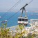 Un teleférico ascendiendo una montaña sobre una ciudad costera